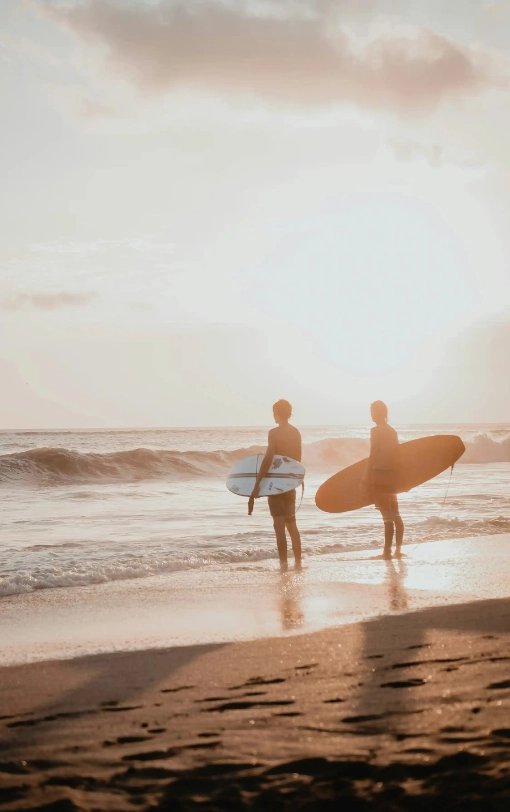 Two surfers standing on the beach at sunset with their boards, representing the Nicaragua Surf Guide.