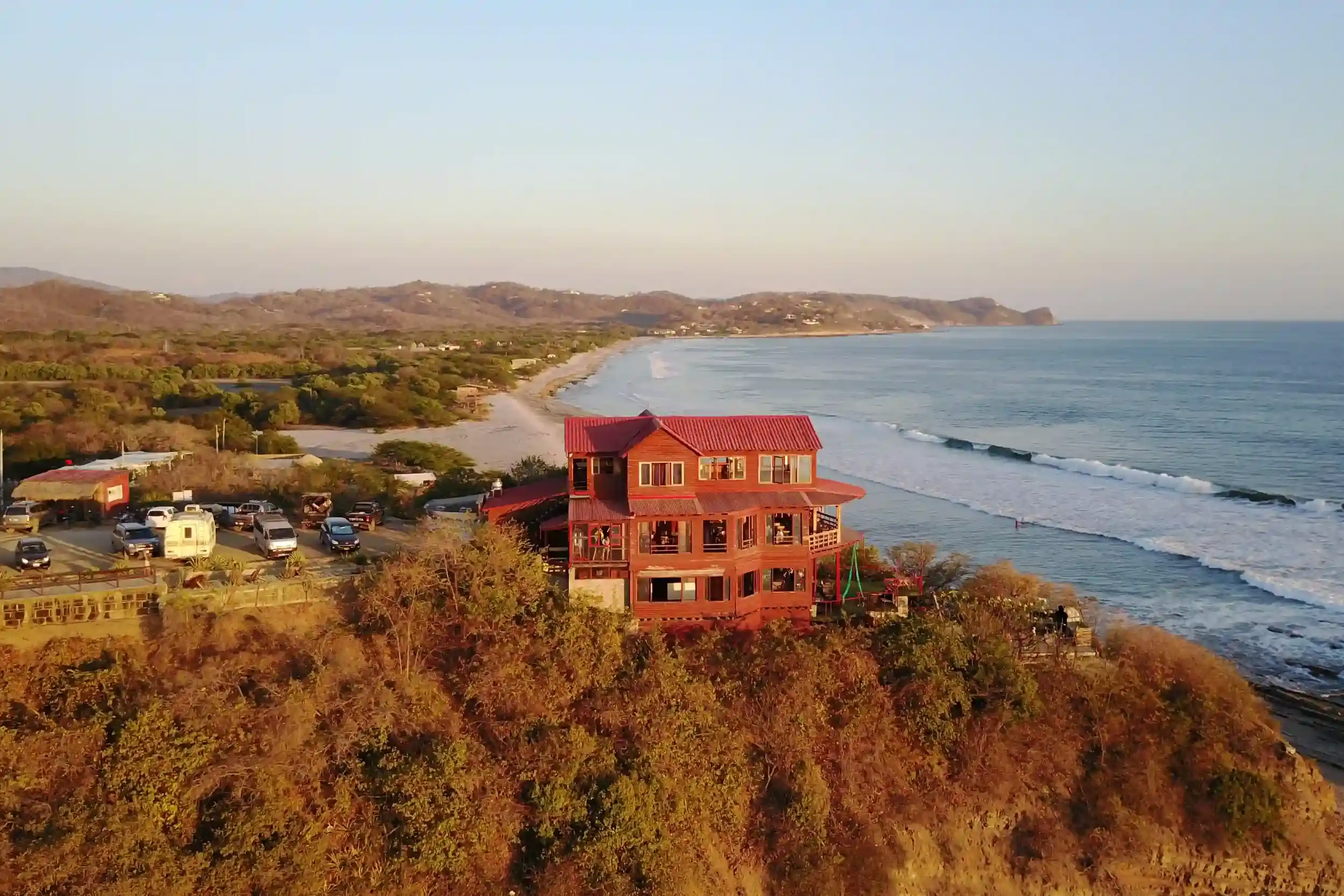 Aerial view of Magnific Rock perched on a cliff overlooking Popoyo beach in Nicaragua, featuring oceanfront surf breaks,