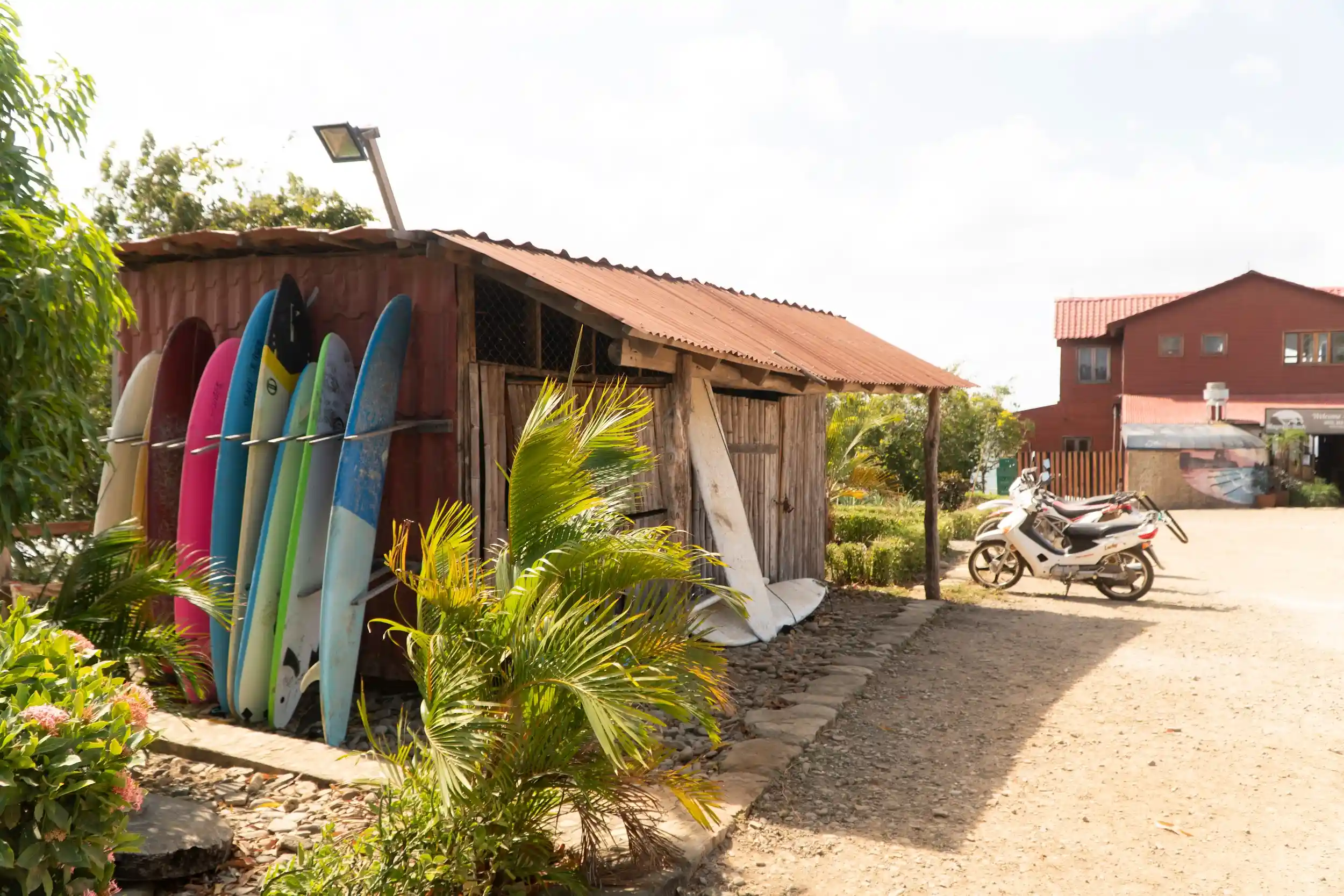 A row of colorful surfboards stored beside a rustic shed near Magnific Rock.
