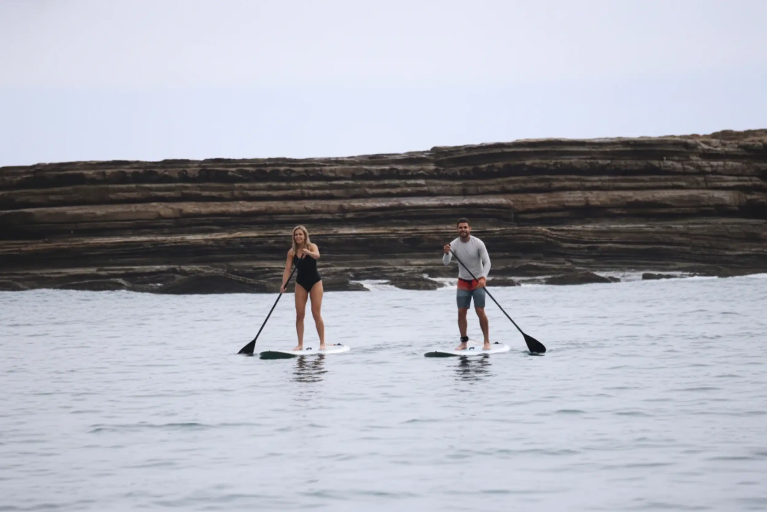 Guests enjoying a relaxing SUP (Stand Up Paddle) session along the calm coastline as part of Nicaragua surf camp activities and services.