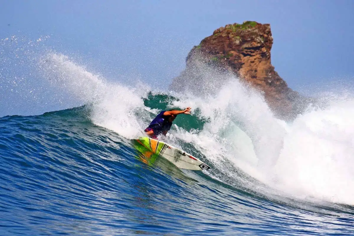 Surfer carving a powerful wave near a rocky point break in Playa Maderas, Nicaragua
