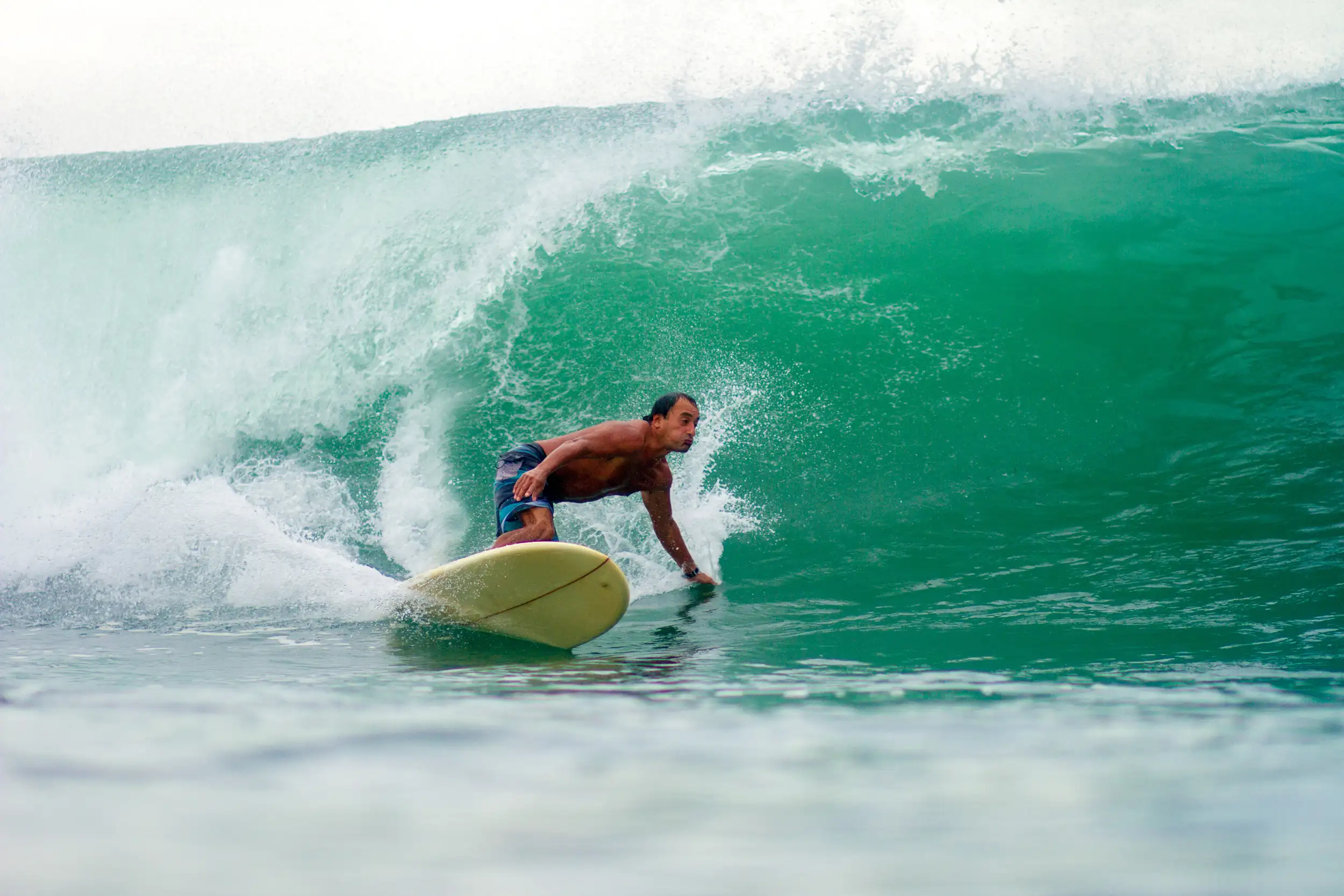 Surfer crouching low while riding a powerful green wave at Playa Santana, with a steep face and heavy spray from a fast-breaking section.