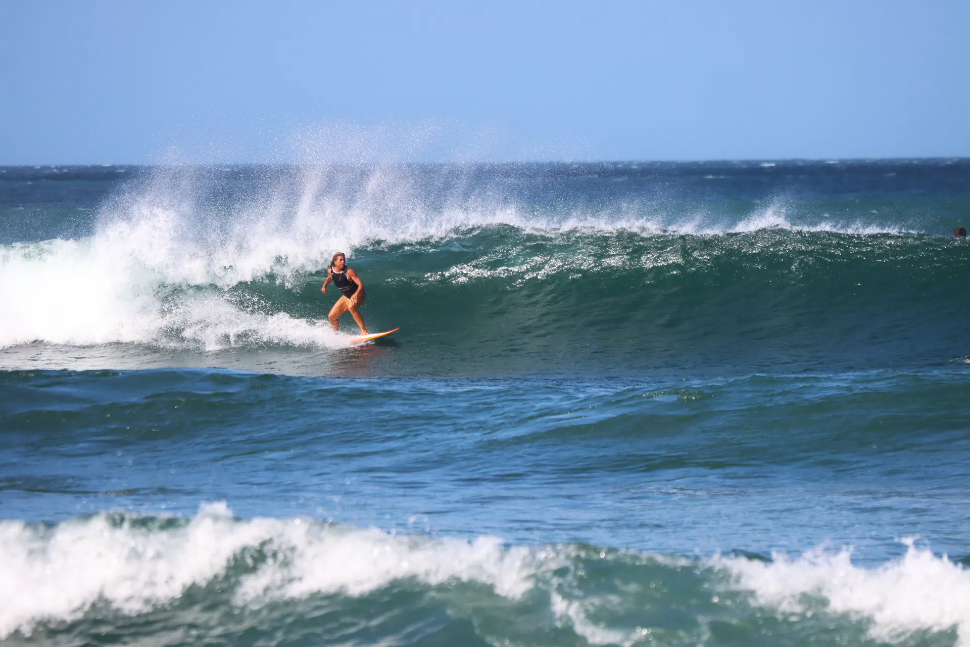 Surfer riding a wave in the ocean with whitewater breaking behind them